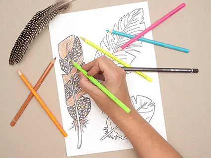 Jemand malt mit einem neongrünen Buntstift von Faber-Castell kleine Punkte auf einer gezeichnete und aquarellierte Vogelfeder aus. Foto: Johanna Rundel
