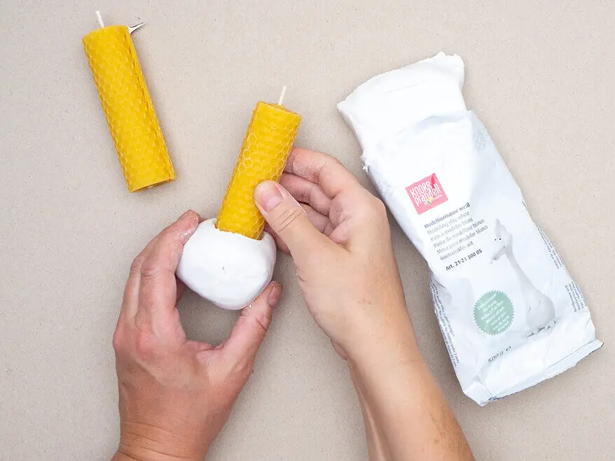 Jemand formt mit einer gerollten Bienenwachskerze einen Kerzenhalter aus lufttrocknender Modelliermasse von KNORR prandell. Foto: Johanna Rundel