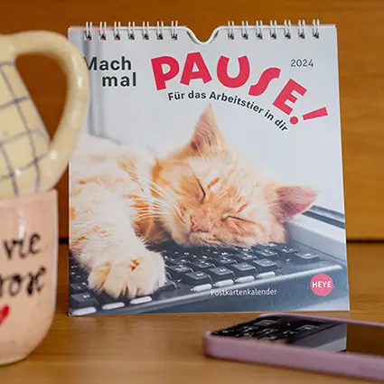 Zwei ineinander gestapelte Kaffeetassen stehen neben einem Aufstellkalender des Athesia Kalenderverlags. Foto: Johanna Rundel