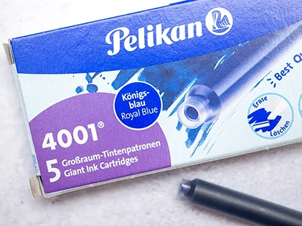 Eine Packung königsblaue Pelikan Großraum-Tintenpatronen liegt auf einem grauen Untergrund. Eine einzelne Patrone liegt daneben. Foto: Johanna Rundel