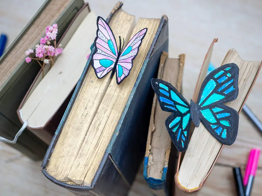 Eine Reihe hochkant gestellter, alter Bücher. Im Buchschnitt stecken zwei Lesezeichen in Schmetterlingsform. Foto: Johanna Rundel