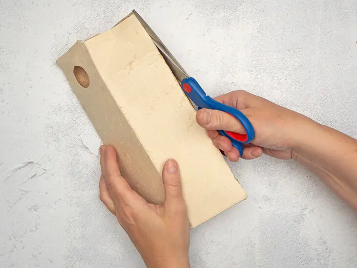 Jemand schneidet mit einer Schere von KNORR prandell eine Milchtüte seitlich auf.