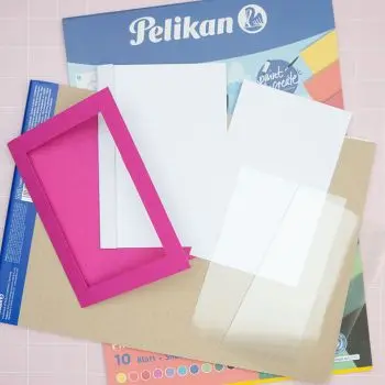 Verschiedene Papiere und Bastelmaterialien von Pelikan liegen auf einem rosa Untergrund. Foto: Johanna Rundel