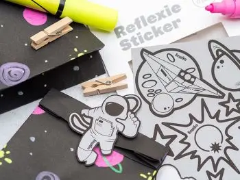 Dunkle Papiertüten, mit Neonmarkern in einem Weltraumlook bemalt. Eine Tüte ist mit einem Reflexie-Sticker von ergobag beklebt. Foto: Johanna Rundel