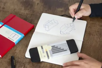 Jemand zeichnet mit einem Kugelschreiber ein abstrahiertes Auto in ein Notizbuch von Moleskine.