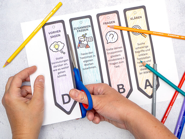 Jemand schneidet mit einer Schere von STAEDTLER Rollenkarten fürs reziproke Lesen aus einem Vordruck aus. Foto: Johanna Rundel