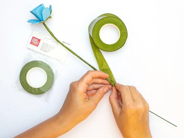 Jemand umwickelt den Stiel einer Blume aus Eierkartons mit grünem Floristenkreppband von KNORR prandell. Foto: Johanna Rundel