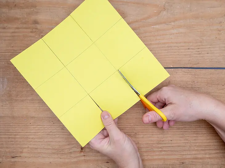 Jemand schneidet mit einer gelben Schere einen gelben Fotokarton von HEYDA für ein Osternest zurecht. Foto: Johanna RundelJemand schneidet mit einer gelben Schere einen gelben Fotokarton von HEYDA für ein Osternest zurecht. Foto: Johanna Rundel