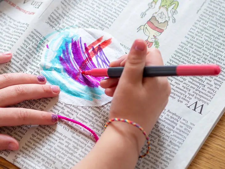 Ein kleines Kind malt mit einem Filzstift einen Kreis aus weißer Strohseide von HEYDA an. Foto: Johanna Rundel