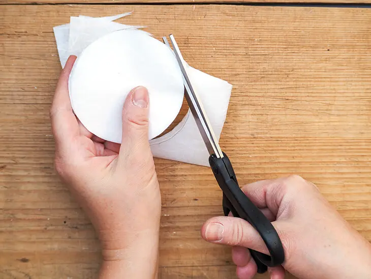 Jemand schneidet Kreise aus weißer Strohseide von HEYDA aus. Foto: Johanna Rundel