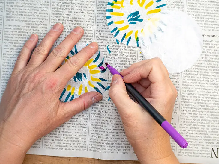 Jemand malt Strohseide-Kreise mit bunten Aquarell-Filzstiften an. Foto: Johanna Rundel