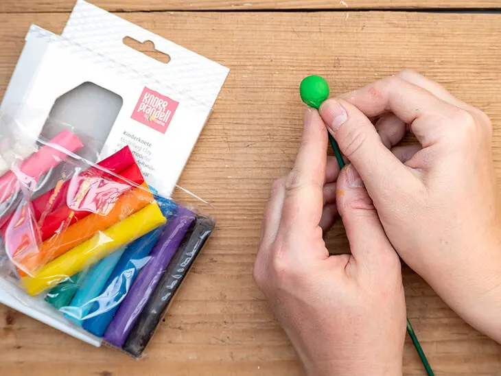 Jemand befestigt eine grüne Kugel aus Kinderknete von HEYDA an einem Schaschlik-Spieß von KNORR prandell. Foto: Johanna Rundel