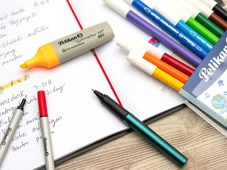 Fineliner, Fasermaler, Textmarker – verschiedene Stifte der Marke Pelikan liegen auf einem schwarzen my.book flex von herlitz. Foto: Johanna Rundel