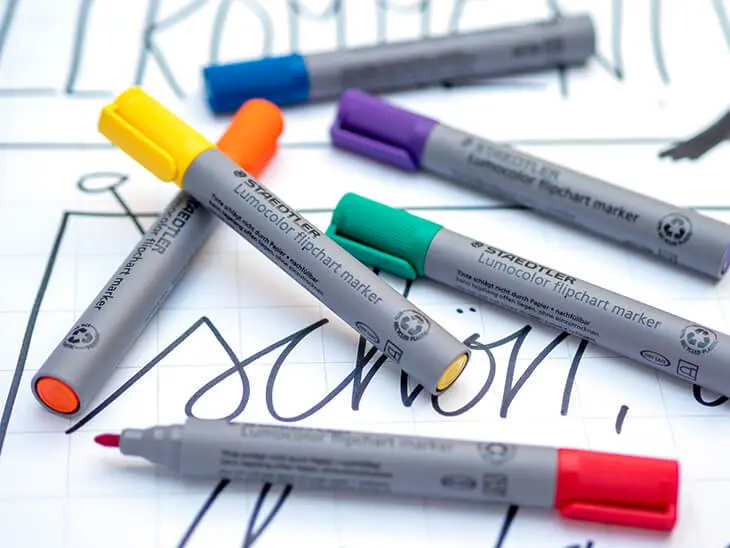 Verschiedenfarbige Flipchartmarker von STAEDTLER liegen auf einem vorgestalteten Flipchart-Bogen. Foto: Johanna Rundel