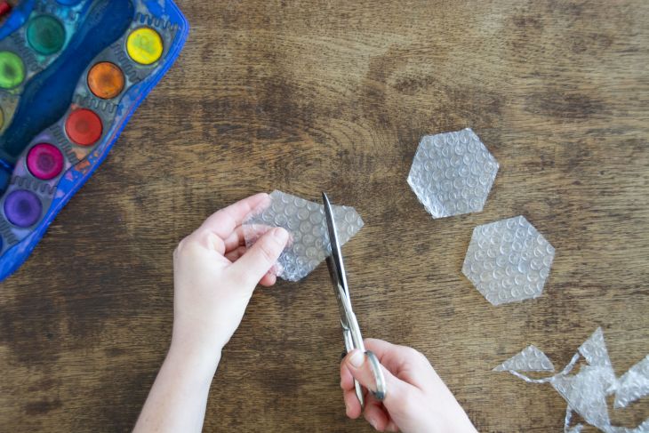 Jemand schneidet Luftpolsterfolie in wabenartigen Formen zurecht.
