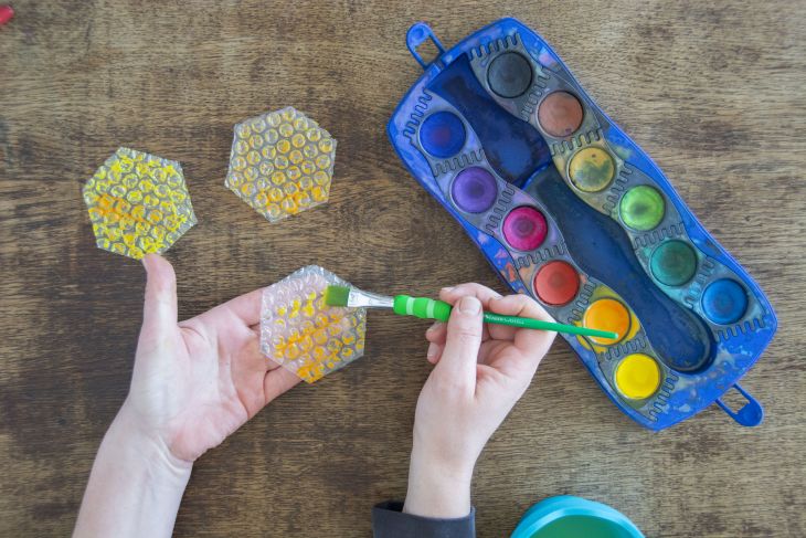 Jemand bemalt Luftpolsterfolie in Wabenform mit Wassermalfarben von Faber-Castell
