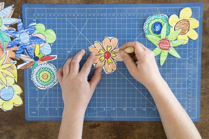 Jemand sticht mit einer Prickelnadel in eine Papierblume.