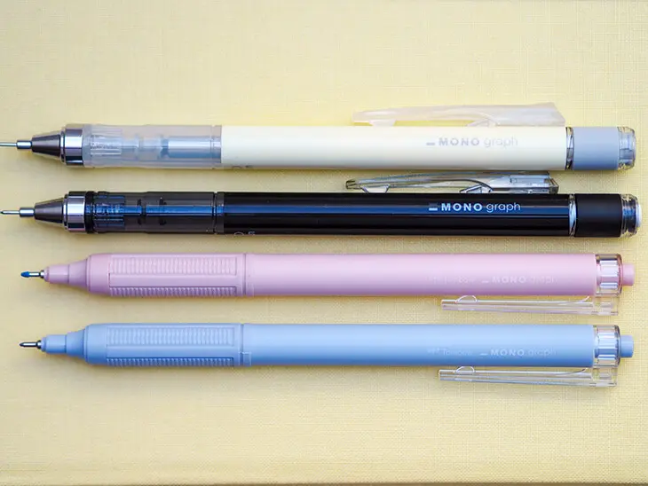 Verschiedene MONO graph mechanical pencils von Tombow liegen auf einem hellgelben Notizbuch mit Leineneinband. Foto: Johanna Rundel