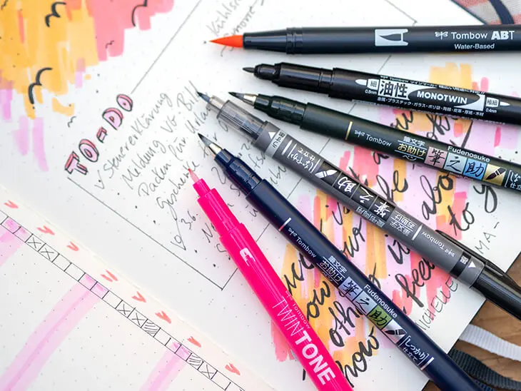 Verschiedene Stifte von Tombow liegen auf einem aufgeschlagenen Bullet Journal. Der Fokus liegt auf den unterschiedlichen Stiftspitzen. Foto: Johanna Rundel