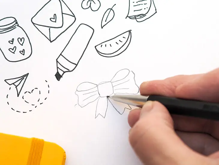 Jemand zeichnet mit einem Drehgriffel No.2 von LEUCHTTURM1917 ein Schleifen-Doodle in ein Notizbuch. Foto: Johanna Rundel