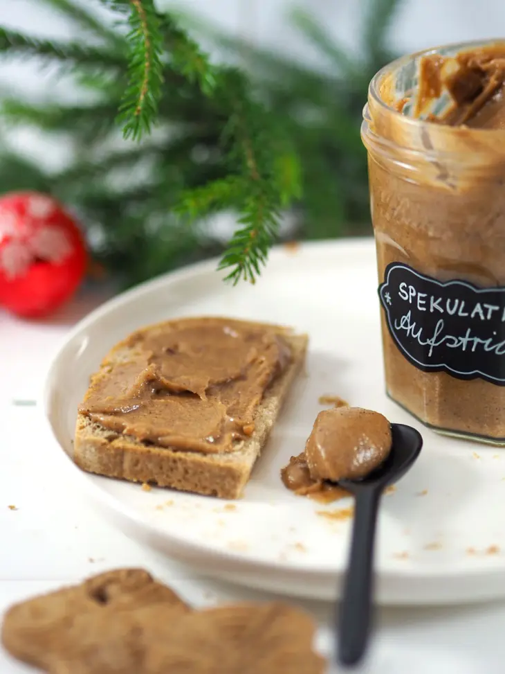 Ein Brot mit selbstgemachtem Spekulatius-Aufstrich liegt auf einem Teller, drumherum liegt Weihnachtsdeko