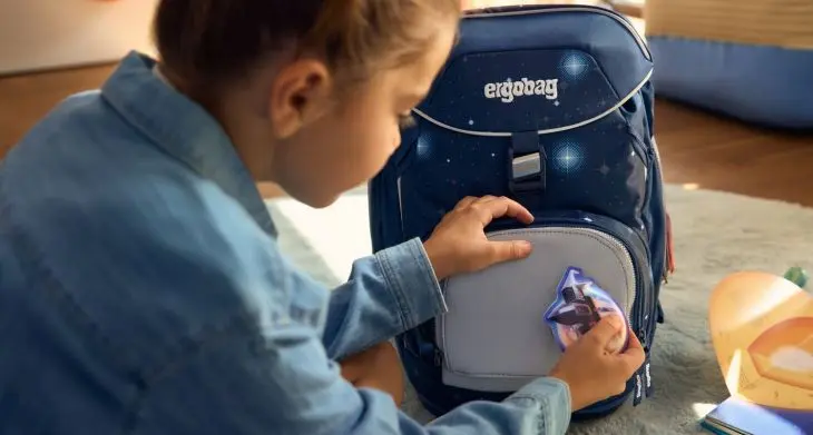 Ein Kind befestigt einen Klettie an seinem Schulranzen von ergobag