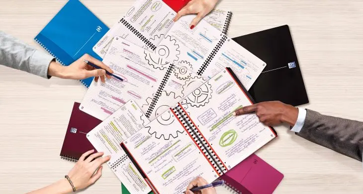 In offen liegende Notizbücher von Oxford sind Notizen und ineinander greifende Zahnräder gemalt