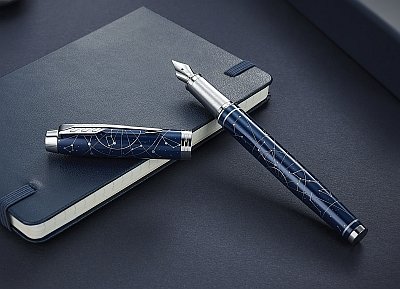 Ein blauer Füller von Parker liegt auf einem dunklen Notizbuch.