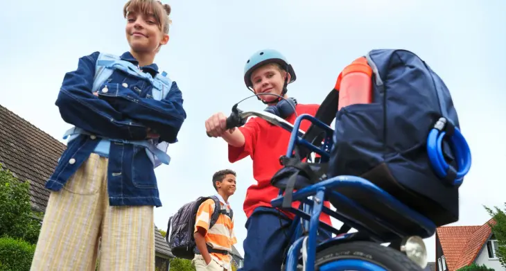 2 Kinder stehen an einem Fahrrad, im Fahrradkorb ist ein Schulrucksack von satch abgestellt