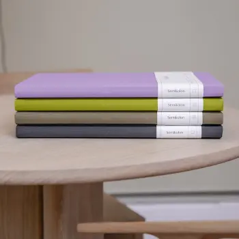 Vier Notizbücher von Semikolon liegen gestapelt auf einem Tisch.