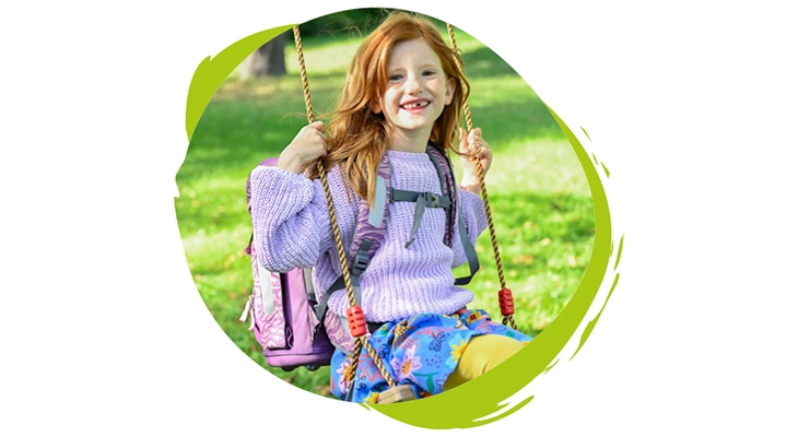 Ein Mädchen sitzt auf einer Schaukel und trägt einen Schulranzen von Step by Step