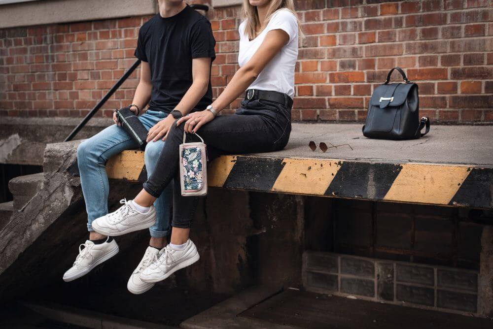 2 Jugendliche sitzen auf einer Treppe und halten jeweils ein Schlampermäppchen in der Hand. 