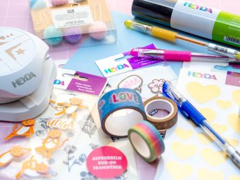 Viele verschiedene Kreativmaterialien der Marken, HEYDA, KNORR prandell und BRUNNEN liegen kreuz und quer auf einem Tisch verteilt. Foto: Johanna Rundel