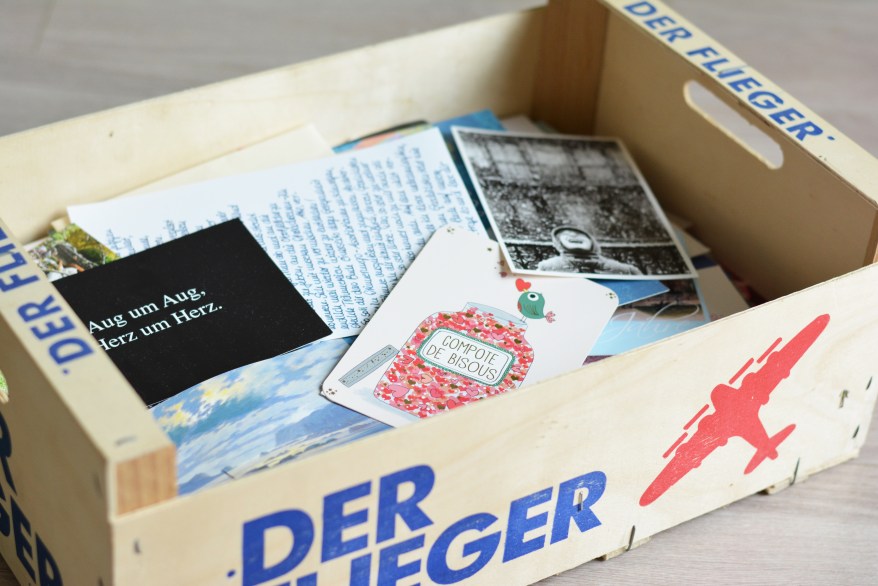 Alte Karten und Briefe in einer Holzkiste mit Aufdruck „Der Flieger“
