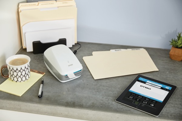 Auf einem Sideboard liegen mehrere Registermappen. Daneben liegt ein Labelwriter der Marke Dymo und ein kleines Tablet zur Bedienung des Labelwriters.