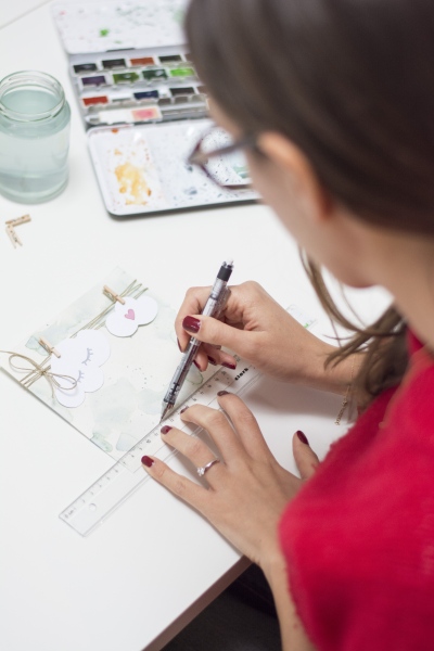 Frau zeichnet mit Lineal und Stift auf selbstgebastelter Karte