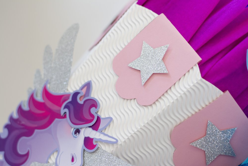 Nahaufnahme vom Rand der Schultüte mit Einhorn und Sternen sowie pinkem Krepppapier.