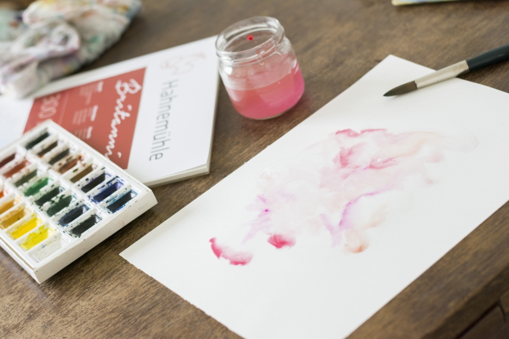 Rosa Aquarellmotive auf Papier mit Wasser und Pinsel gemalt