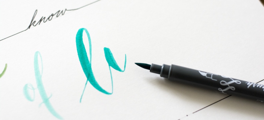 Türkises Brushlettering mit Brushpen auf weißem Papier.