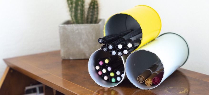 Drei liegende, mit Stiften gefüllte, Stiftehalter aus bunten recycelten Dosen.