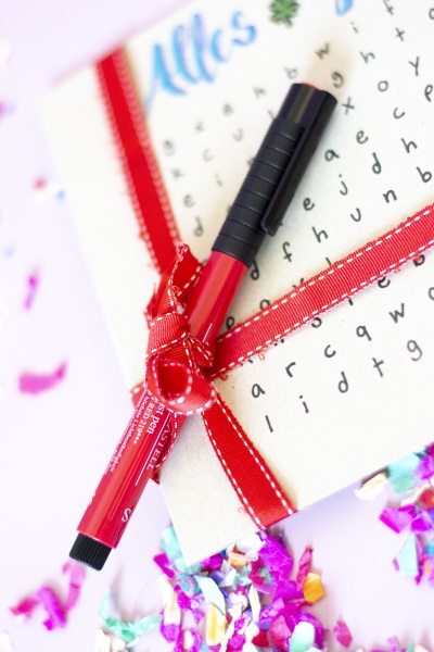 Suchspiel-Karte, an die mit einem roten Band ein roter Stift befestigt wurde.