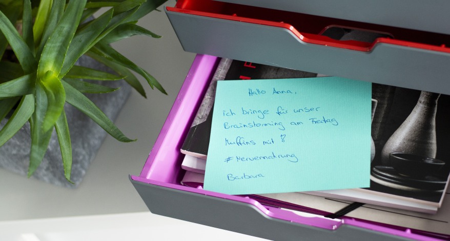 In einer geöffneten Schublade einer Schubladenbox liegt ein Zettel mit einer Notiz