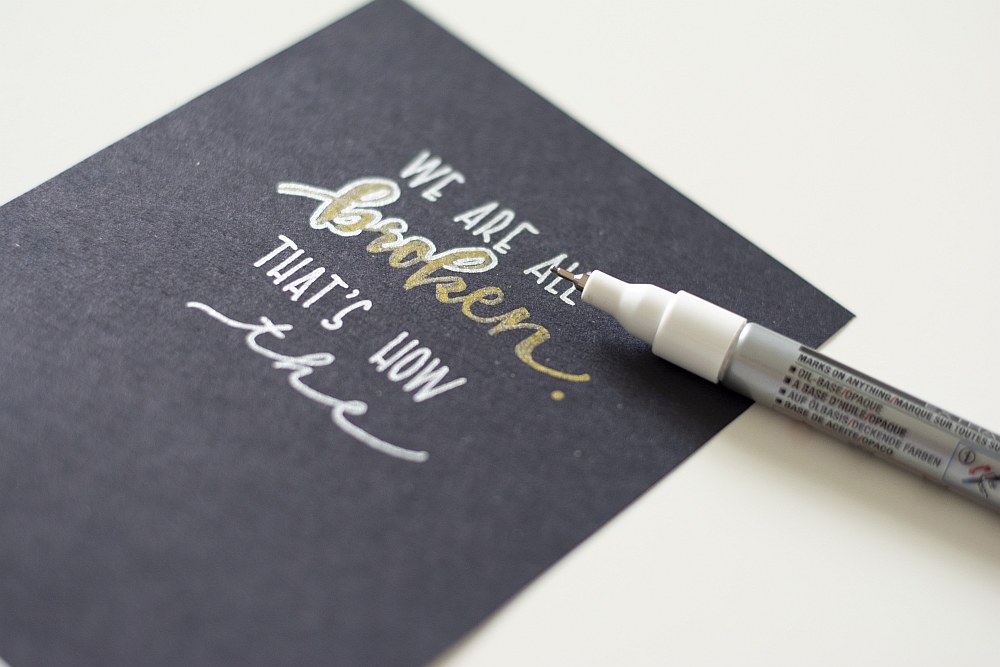 Handlettering „We are all broken…“ auf schwarzer Karte mit weißem Marker hervorgehoben.