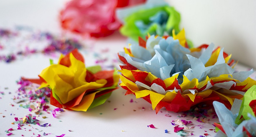 Bunte Papierblumen und Konfetti als festliche Tischdeko