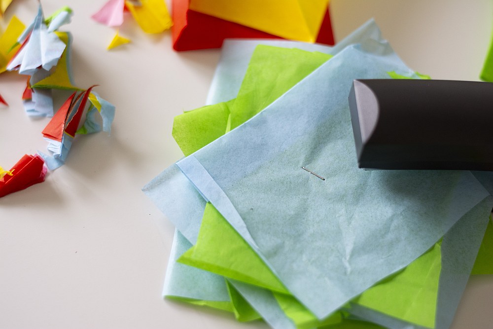 Papierlagen in Grün und Blau werden mit einem Tacker fixiert