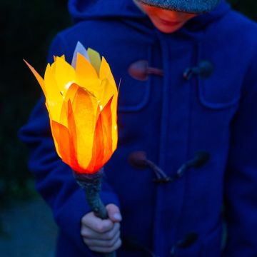 Ein Kind hält eine LED Fackel aus PET-Flasche in der Hand, die hell leuchtet.