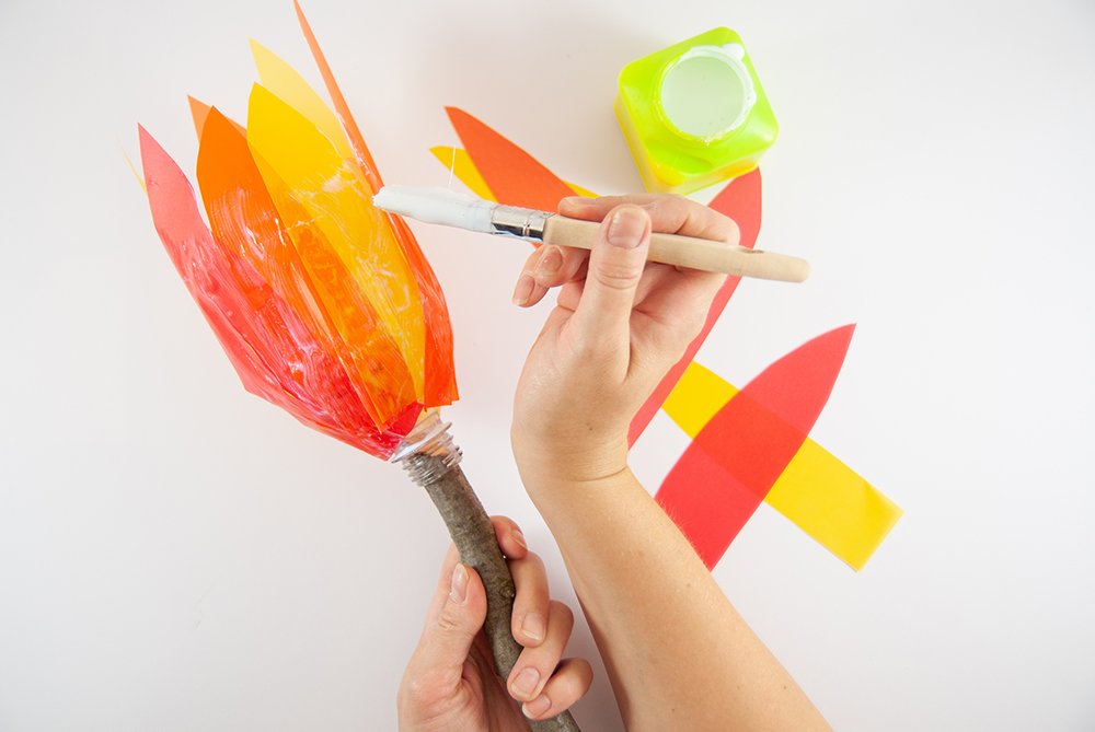 Auf einen umgedrehten Flaschenhals werden Flammen aus Transparentpapier geklebt.