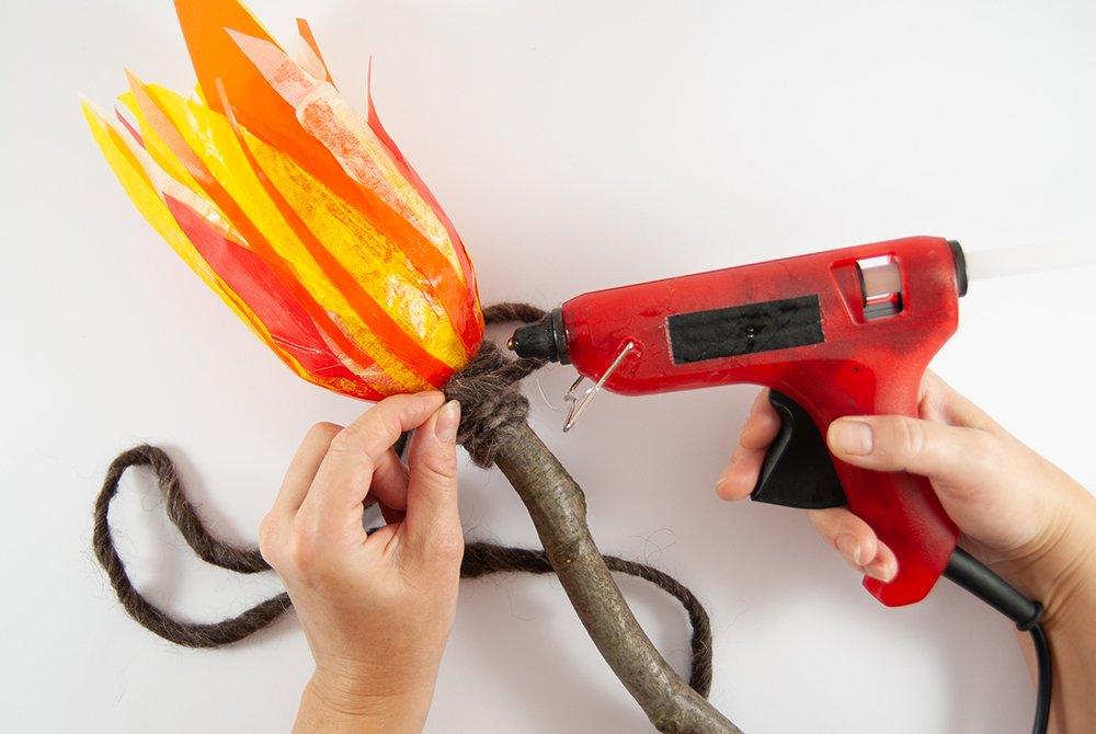 Eine Filzschnur wird mit einer Heißklebepistole auf eine LED-Fackel aus PET-Flaschen geklebt.