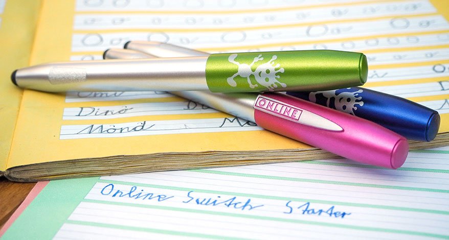 Drei Schreiblernfüller von Online liegen auf ausgefüllten Schreinblernheften.