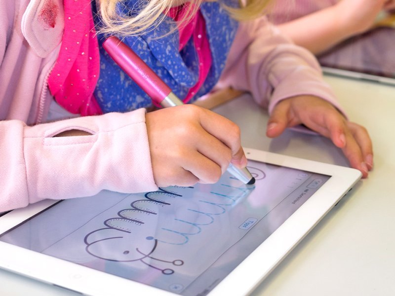 Ein Mädchen malt mit einem Stift mit Stylusaufsatz von Online auf ein Tablet.